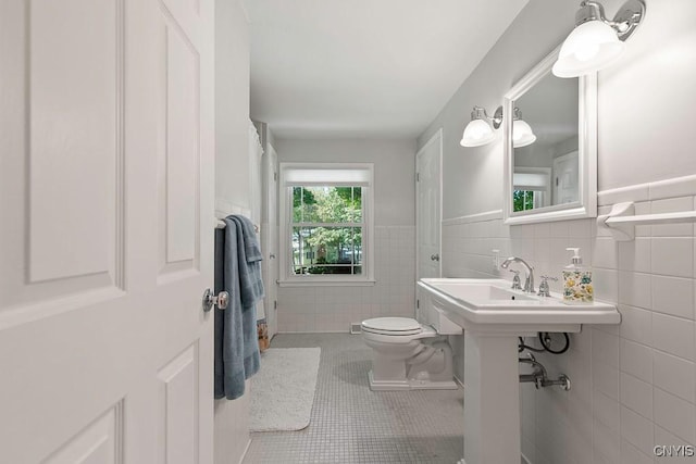 bathroom featuring tile patterned flooring, toilet, and tile walls