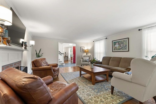 living room featuring a fireplace, hardwood / wood-style flooring, and crown molding