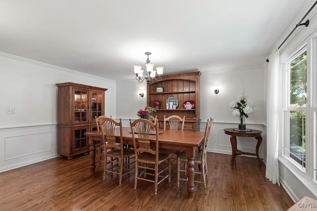 dining area with ornamental molding, dark hardwood / wood-style floors, and an inviting chandelier