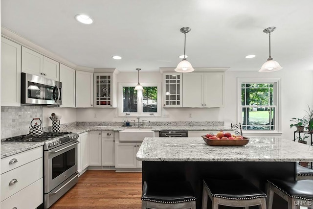 kitchen featuring sink, stainless steel appliances, pendant lighting, a kitchen bar, and hardwood / wood-style flooring