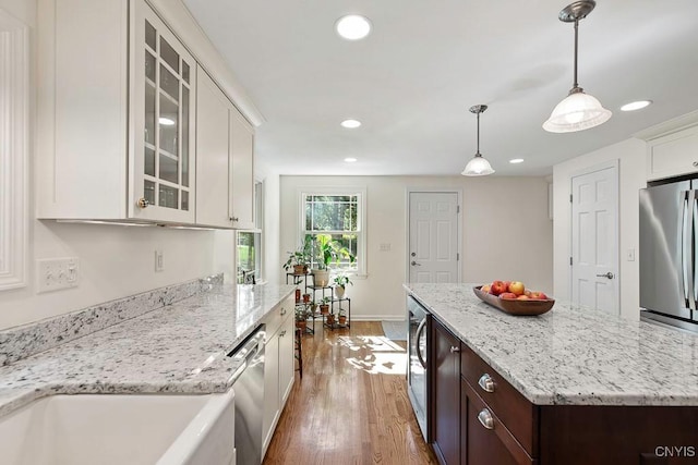 kitchen featuring dark brown cabinetry, stainless steel appliances, pendant lighting, wood-type flooring, and white cabinets