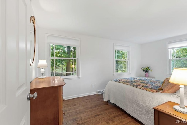 bedroom with dark wood-type flooring and multiple windows