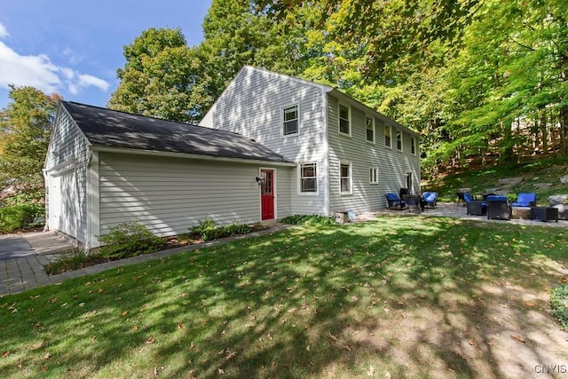 back of property with a lawn, a patio area, and a garage