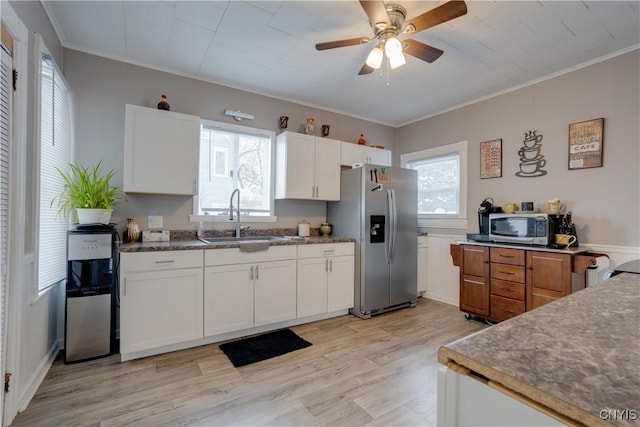 kitchen with sink, stainless steel refrigerator with ice dispenser, crown molding, white cabinets, and light wood-type flooring