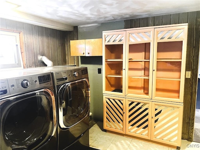 laundry area with cabinets, washer and clothes dryer, and wooden walls