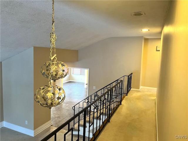 corridor featuring carpet flooring, a textured ceiling, and vaulted ceiling