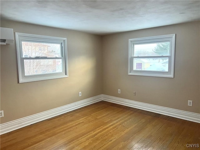 empty room with a wall unit AC and light hardwood / wood-style flooring