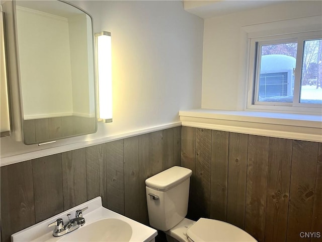 bathroom with toilet, sink, and wooden walls