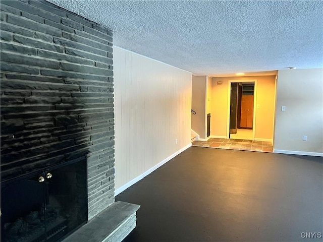 unfurnished living room with wood walls, a large fireplace, and a textured ceiling