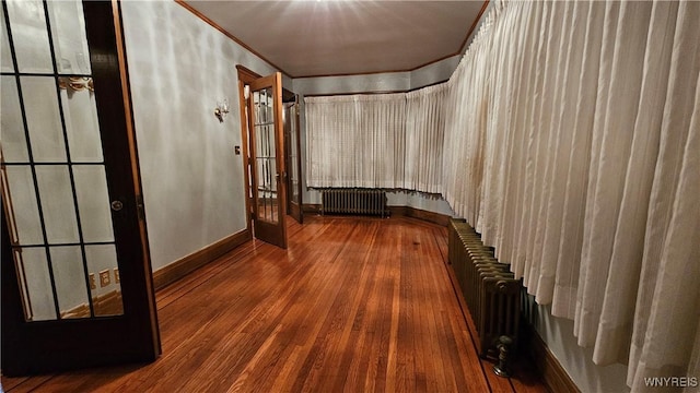 corridor with french doors, radiator, crown molding, and wood-type flooring