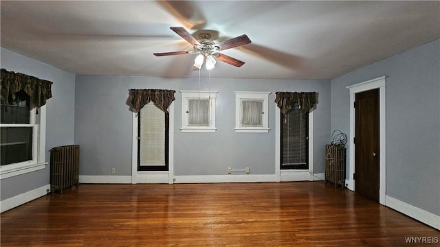 spare room with dark hardwood / wood-style floors, ceiling fan, and radiator heating unit