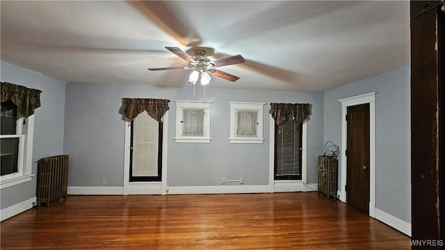 unfurnished living room featuring dark hardwood / wood-style floors, ceiling fan, and radiator