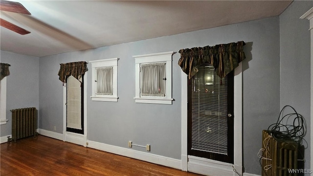 spare room with ceiling fan, radiator heating unit, and dark wood-type flooring