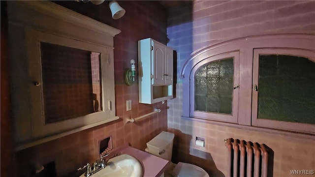 interior space with vanity, backsplash, toilet, and radiator