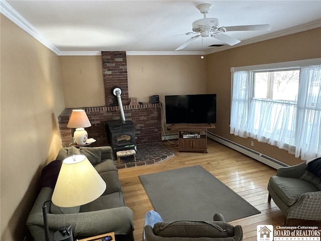 living room featuring light wood-type flooring, ceiling fan, crown molding, a baseboard radiator, and a wood stove