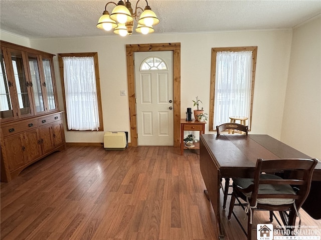 dining area featuring crown molding, dark hardwood / wood-style flooring, a textured ceiling, and an inviting chandelier