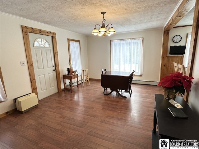 dining space featuring baseboard heating, dark wood-type flooring, a chandelier, and a textured ceiling