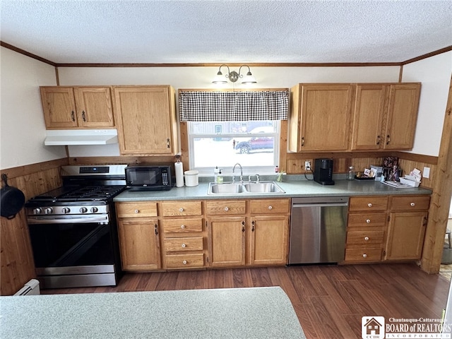 kitchen with dark hardwood / wood-style flooring, a textured ceiling, stainless steel appliances, sink, and wood walls