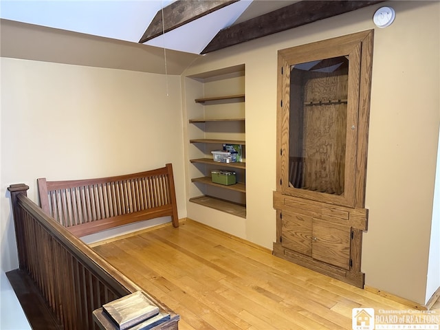 stairway with vaulted ceiling with beams, built in shelves, and hardwood / wood-style floors