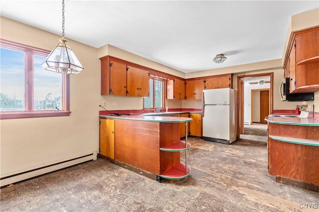 kitchen with decorative light fixtures, white refrigerator, baseboard heating, and a wealth of natural light