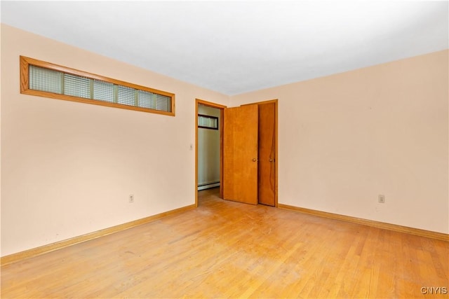 empty room featuring baseboard heating and light hardwood / wood-style flooring