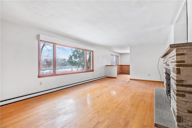 unfurnished living room featuring baseboard heating and light hardwood / wood-style flooring