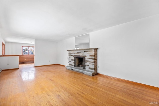 unfurnished living room featuring a stone fireplace, light wood-type flooring, and a baseboard radiator