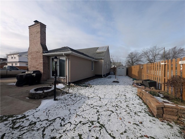 view of snow covered exterior featuring a shed and a fire pit