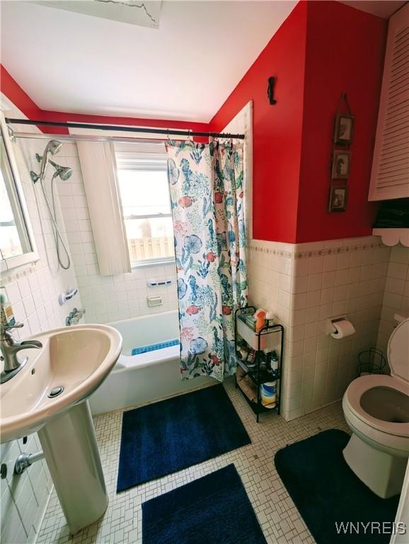 bathroom featuring tile walls, tile patterned flooring, shower / bath combination with curtain, and toilet