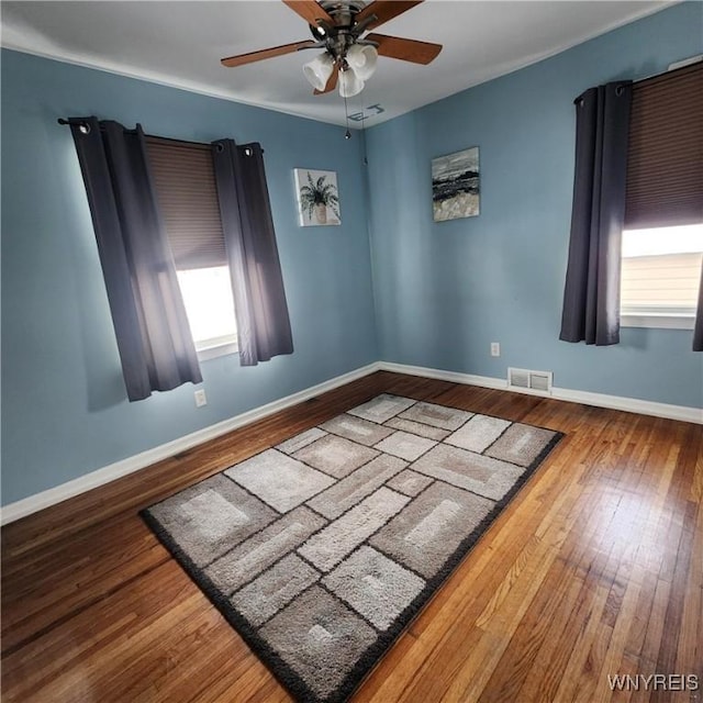 empty room with hardwood / wood-style flooring, a wealth of natural light, and ceiling fan