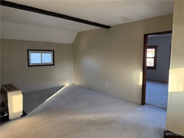 spare room with vaulted ceiling with beams, wood walls, heating unit, and carpet floors