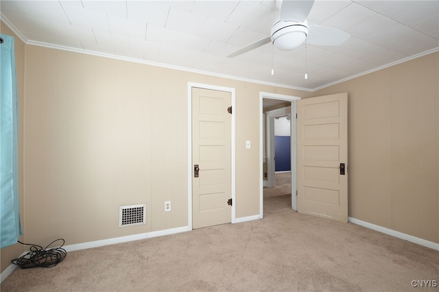 empty room featuring ceiling fan, crown molding, and light carpet