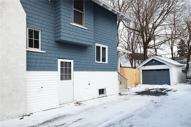 view of snow covered exterior featuring an outbuilding and a garage