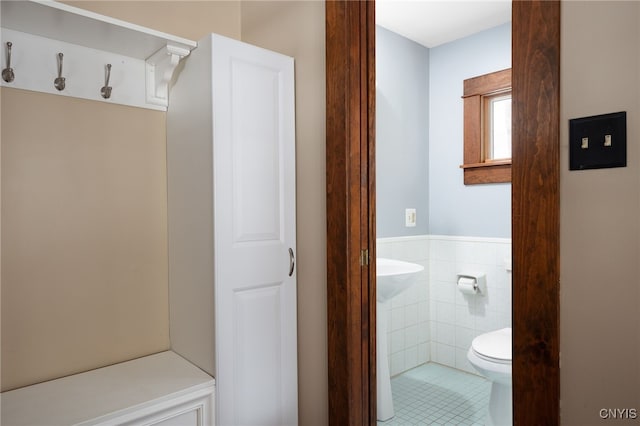 bathroom featuring toilet and tile walls