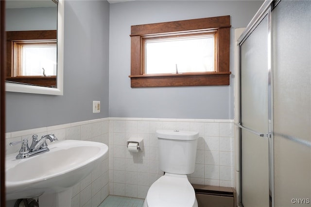 bathroom featuring tile walls, toilet, walk in shower, and sink