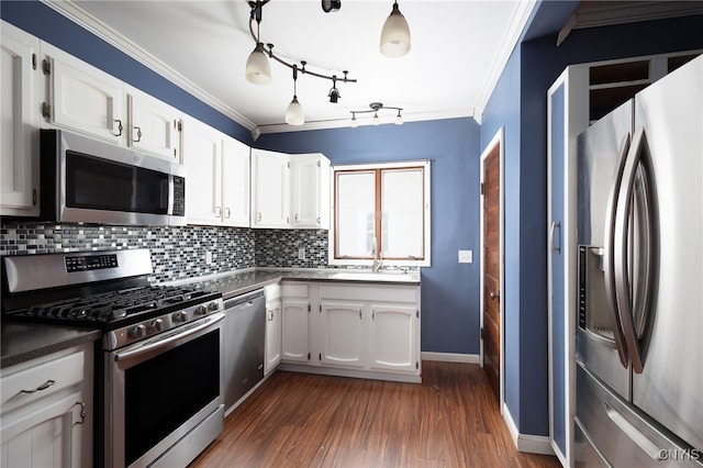 kitchen featuring dark wood-type flooring, appliances with stainless steel finishes, decorative backsplash, white cabinets, and ornamental molding