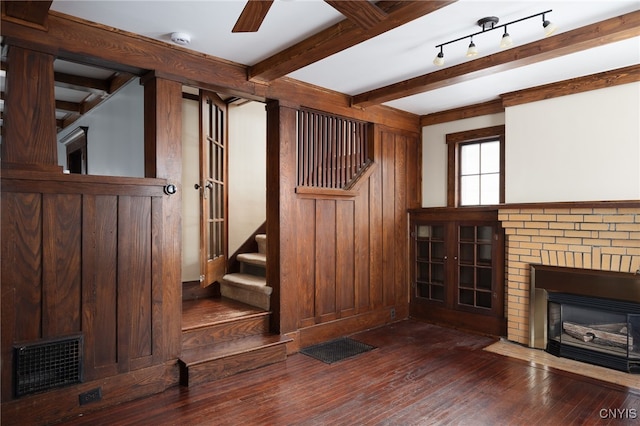 interior space featuring dark hardwood / wood-style floors, beam ceiling, a fireplace, and wooden walls