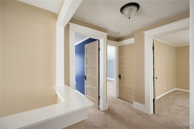 corridor with ornamental molding and light carpet