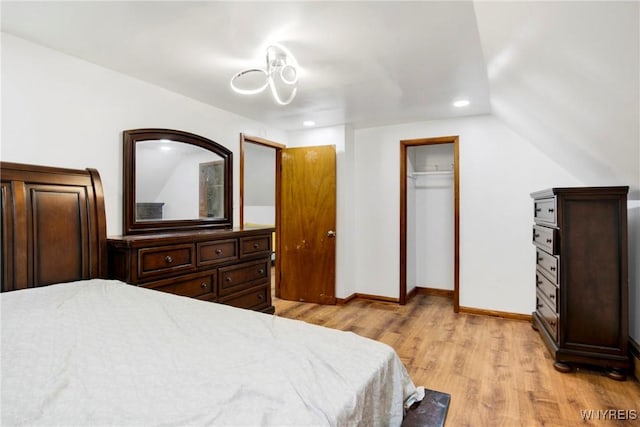 bedroom featuring light hardwood / wood-style floors, lofted ceiling, and a closet