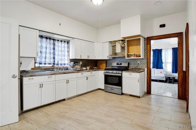 kitchen featuring white cabinetry, wall chimney range hood, sink, and stainless steel stove