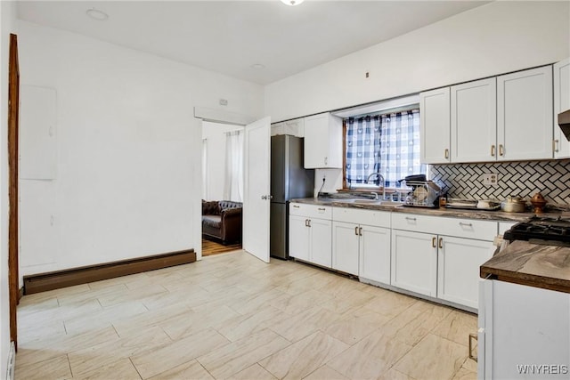 kitchen with sink, decorative backsplash, stainless steel fridge, a baseboard radiator, and white cabinetry