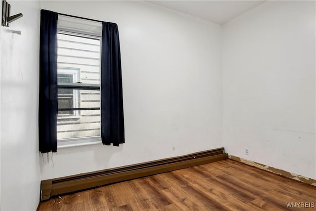 unfurnished room with wood-type flooring and a baseboard radiator