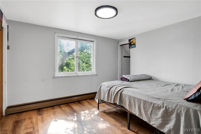 bedroom featuring a baseboard radiator and hardwood / wood-style flooring