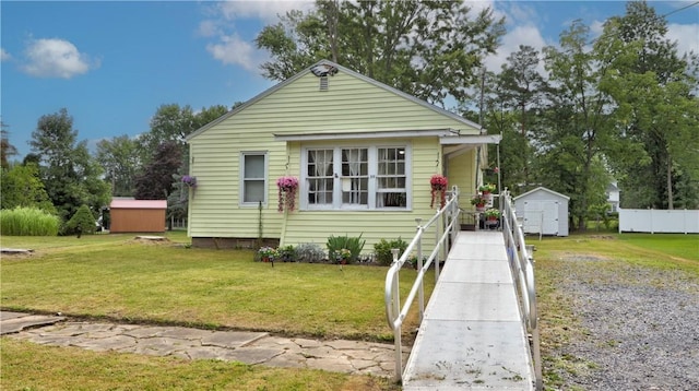 bungalow-style home with a front lawn and a shed