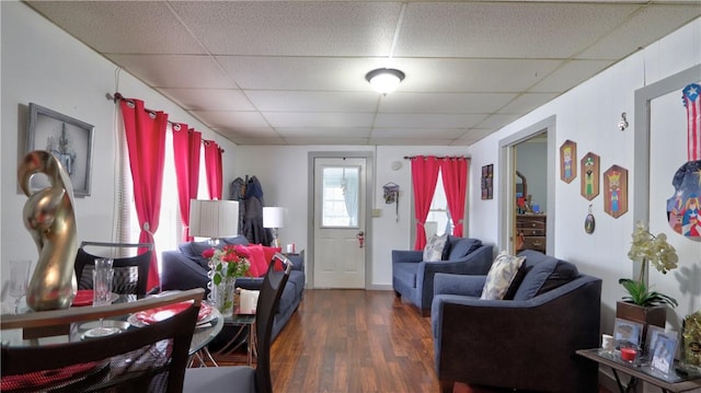 living room with dark hardwood / wood-style floors and a drop ceiling