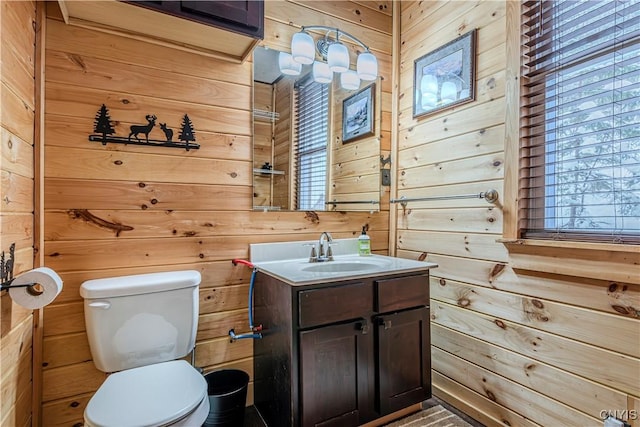 bathroom with toilet, vanity, and wood walls