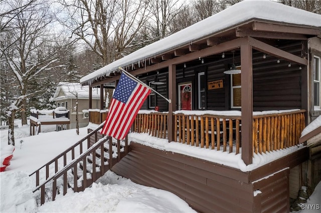 snow covered deck featuring a porch