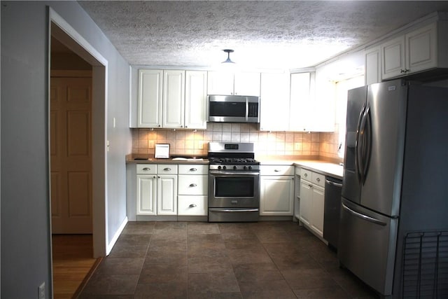 kitchen featuring tasteful backsplash, white cabinetry, stainless steel appliances, and a textured ceiling