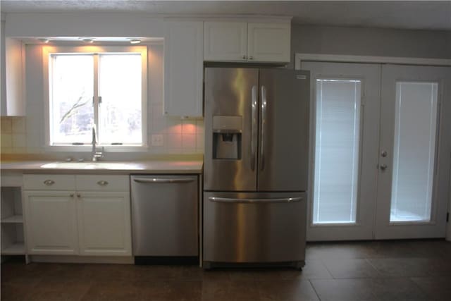 kitchen featuring french doors, white cabinets, sink, decorative backsplash, and appliances with stainless steel finishes