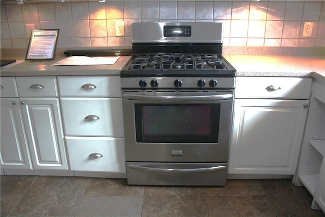 kitchen featuring decorative backsplash, stainless steel gas stove, and white cabinetry